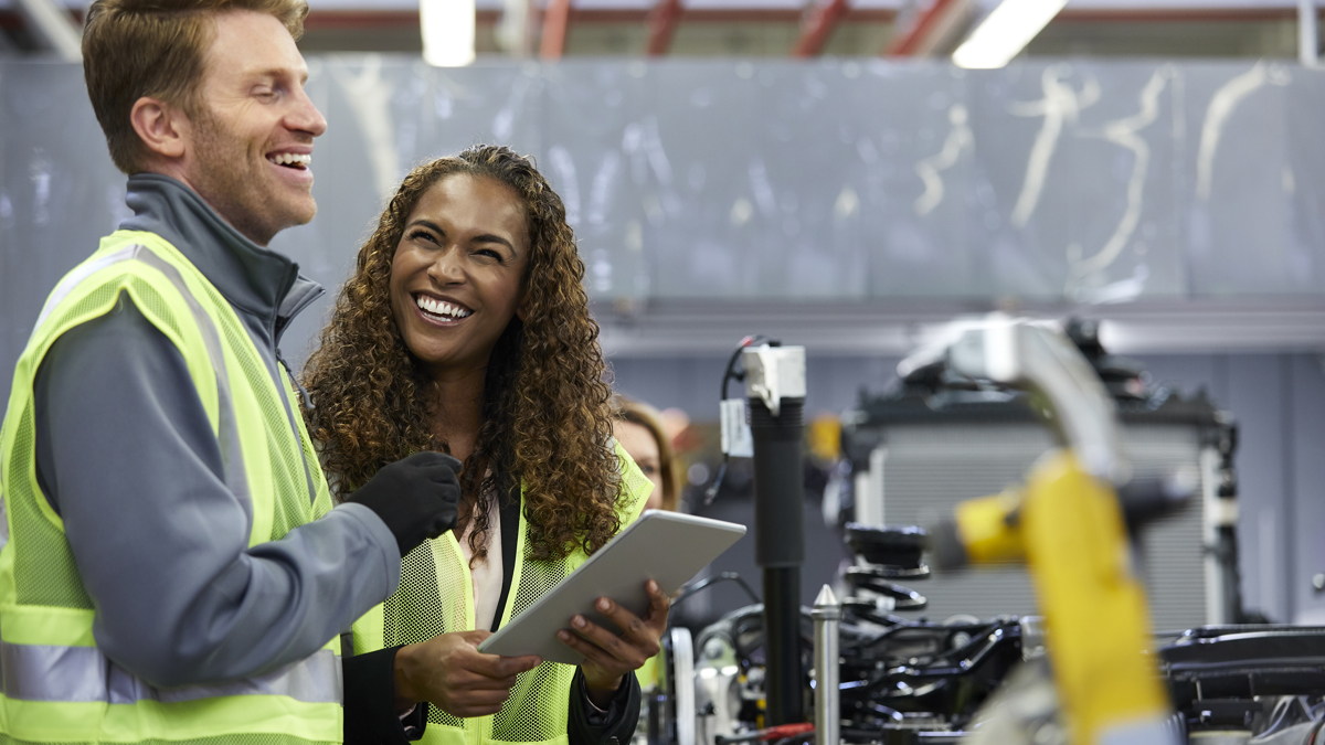 Två arbetare i varselvästar skrattar tillsammans.