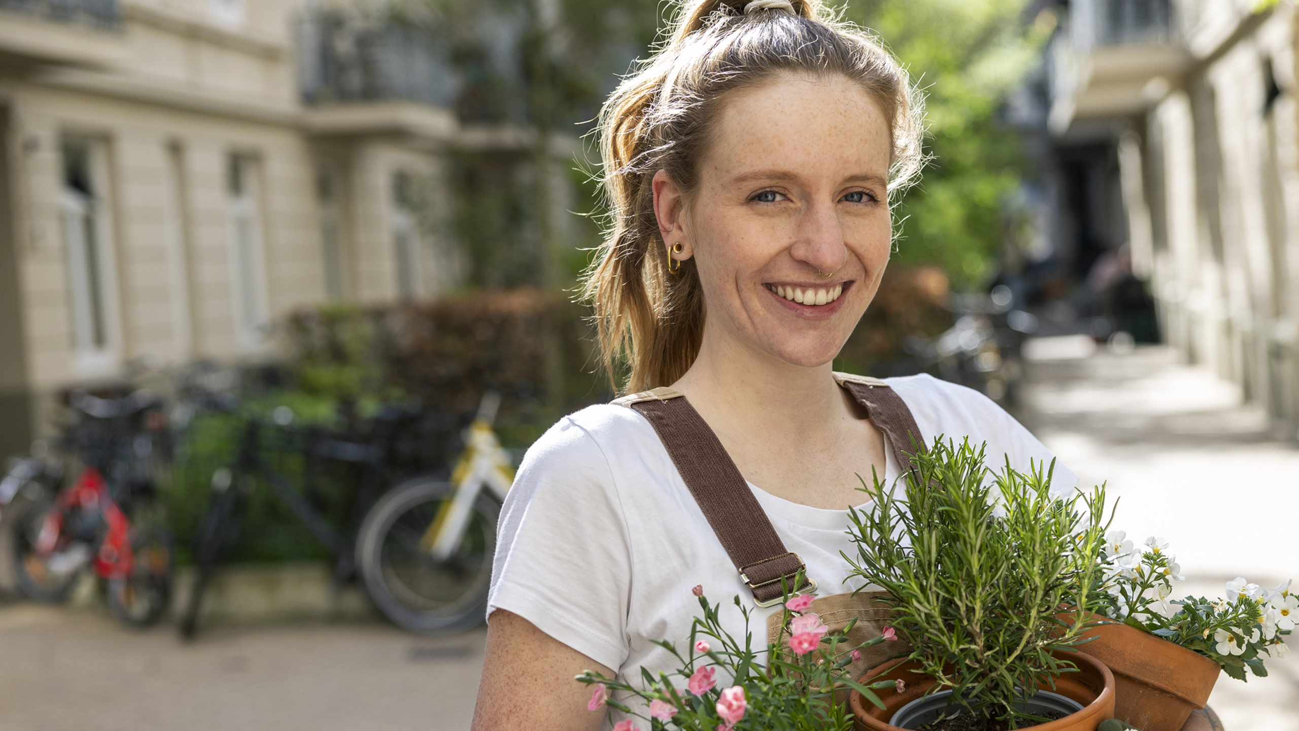En kvinna med krukor i händerna ler mot kameran.