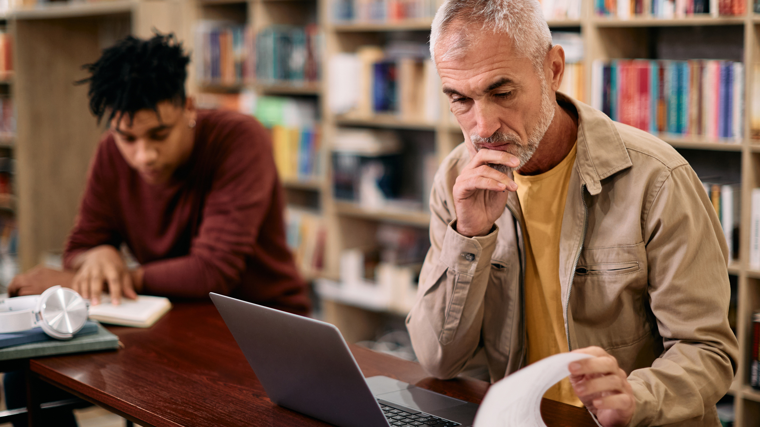 Två män läser på ett bibliotek.