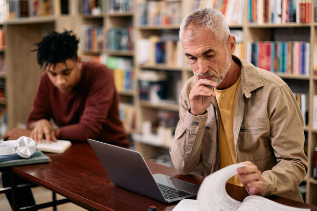 En man sitter vid datorn och funderar.