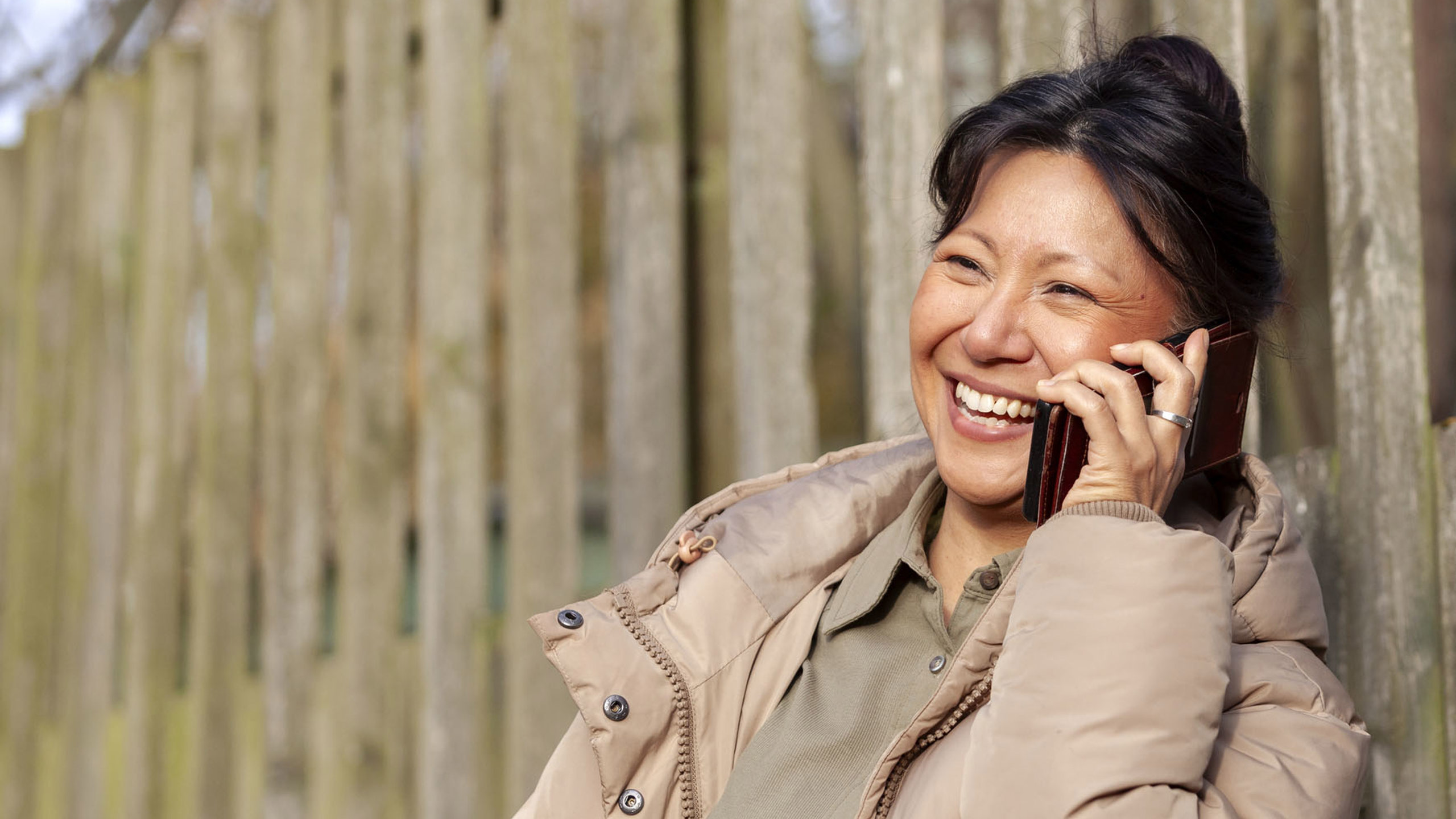 Glad kvinna pratar i telefon.