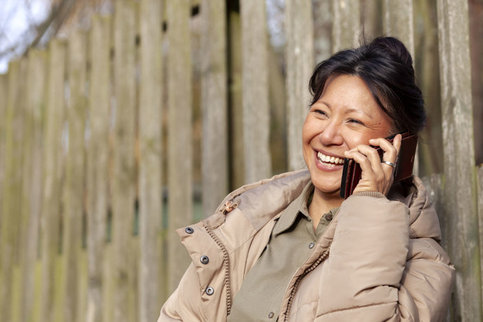 Glad kvinna pratar i telefon.